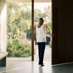 Professional woman opening a door to a sunlit garden, symbolizing financial opportunity.